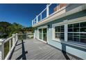 A spacious deck with modern cable railing offers picturesque views of the surrounding landscape and clear blue sky at 160 Shore Dr, Palm Harbor, FL 34683