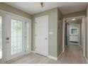 Light and airy hallway featuring wood-look floors, decorative front door and updated lighting at 1960 Canadiana Ct, Dunedin, FL 34698