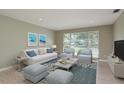 Comfortable living room featuring neutral paint, wood-look flooring and a large window for natural light at 1960 Canadiana Ct, Dunedin, FL 34698