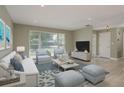 Inviting living room with neutral paint, wood-look flooring and large window for natural light at 1960 Canadiana Ct, Dunedin, FL 34698