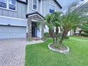 Welcoming front entrance featuring a stone facade and a beautifully landscaped yard with a mature palm tree at 2798 Hilliard Dr, Wesley Chapel, FL 33543