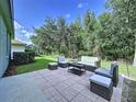 Outdoor patio area complete with cushioned seating and mature trees at 4116 Knollpoint Dr, Wesley Chapel, FL 33544