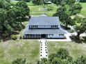 Expansive aerial view of a light blue two-story home with mature trees, long driveway and a beautiful green lawn at 5007 Booth Rd, Plant City, FL 33565
