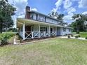 Inviting two-story home featuring a large, covered front porch with white railings and well-manicured landscaping at 5007 Booth Rd, Plant City, FL 33565