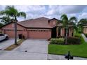 Well-manicured lawn and landscaping accent this lovely home with a terracotta roof and two-car garage at 5663 Sunset Falls Dr, Apollo Beach, FL 33572