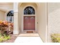 Inviting entryway showcases double doors, arched windows, and colorful plants at 9242 Brindlewood Dr, Odessa, FL 33556