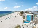 Aerial view showcases Island Inn condos with its pool alongside the pristine beach and beautiful ocean waters at 9980 Gulf Blvd # 408, Treasure Island, FL 33706