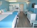 Comfortable hotel room with two beds, kitchenette, dining area, and light blue accent wall at 9980 Gulf Blvd # 408, Treasure Island, FL 33706