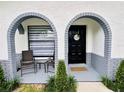 Close up of arched entry with seating area and decorative door, welcome mat and shrubbery at 13186 Thrush St, Spring Hill, FL 34609