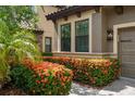 Close-up of home's facade featuring vibrant flower bushes and well-manicured landscaping at 1391 Marinella Dr, Palm Harbor, FL 34683