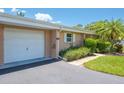 Villa with an attached garage featuring a well-manicured lawn and lush landscaping at 1510 Palmer Ct, Palm Harbor, FL 34685
