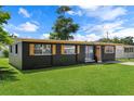 Beautifully renovated single story home with dark exterior, decorative shutters, and a lush front yard at 1707 Windsor Way, Tampa, FL 33619