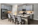 Stylish kitchen featuring gray cabinets, stainless steel appliances, and a breakfast bar with seating at 17140 Holly Well Ave, Wimauma, FL 33598
