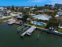 Waterfront home with a private dock, boat lift, and inviting swimming pool, surrounded by lush landscaping at 202 Howard Dr, Belleair Beach, FL 33786