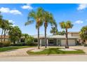 Charming single-story home featuring lush landscaping and a circular driveway lined with palm trees at 202 Howard Dr, Belleair Beach, FL 33786