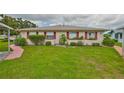 Well-manicured front lawn with green bushes and flowers in front of this tan-sided single story home at 304 Fowling Ct # A, Sun City Center, FL 33573