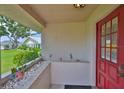 Covered front porch with a red door, textured walls, and a view of a well-kept lawn at 304 Fowling Ct # A, Sun City Center, FL 33573