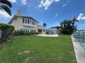 Back exterior view of the home featuring an outdoor pool, green grass, and waterfront access at 413 Midway Is, Clearwater Beach, FL 33767