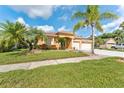 Inviting single-story home featuring a two-car garage, mature palm trees, and a well-kept lawn at 5309 Spectacular Bid Dr, Wesley Chapel, FL 33544