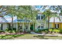 Beautifully landscaped front yard with mature trees and a charming two-story home with a welcoming front porch at 5518 Luminar Pointe Ln, Apollo Beach, FL 33572