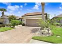 Attractive home showcasing a brick driveway, manicured lawn, and a well-maintained two-car garage at 8605 Grand Alberato Rd, Tampa, FL 33647