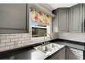 Kitchen featuring a stainless steel sink, gray cabinetry, and a floral window curtain at 915 S Miller Rd, Valrico, FL 33594