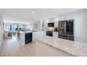 Modern, bright kitchen with stainless steel appliances, granite counters, and an island, open to the living area at 14950 Gulf Blvd # 902, Madeira Beach, FL 33708