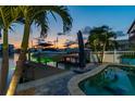 Dusk view of waterfront home featuring lush palms, well lit boat dock, and tranquil pool area at 16106 6Th E St, Redington Beach, FL 33708
