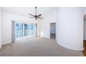 Spacious living room with carpet, fan, and a sliding glass door leading to a balcony with plenty of natural light at 19717 Gulf Blvd # V5, Indian Shores, FL 33785