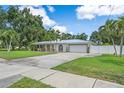 Beautiful single-story home boasts well-manicured lawn, mature trees, and a paved driveway with a two-car garage at 2820 Whitney Rd, Clearwater, FL 33760