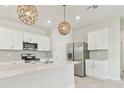 Modern kitchen with a large island, stainless steel appliances, and stylish pendant lighting at 2885 Deer Pine Trl, Land O Lakes, FL 34638