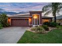Dusk view of single-story home featuring a well-maintained lawn and an attached two-car garage at 31244 Baclan Dr, Wesley Chapel, FL 33545