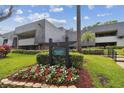 Condominium building featuring a well-maintained lawn, colorful flower beds, and a community sign at 36750 Us 19 N # 09208, Palm Harbor, FL 34684
