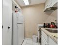 A compact kitchen featuring white appliances, cabinetry, and bright tile floors at 36750 Us 19 N # 09208, Palm Harbor, FL 34684