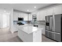 Modern kitchen featuring stainless steel appliances, white cabinetry, and a large center island at 6133 Wire Grass Ct, Nokomis, FL 34275