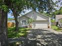 Inviting single-story home with a spacious two-car garage and landscaped front yard, shaded by mature trees at 6203 Calamari Pl, Riverview, FL 33578