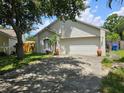 Attractive single-story house showcasing a two-car garage, complemented by mature trees and a well-kept lawn at 6203 Calamari Pl, Riverview, FL 33578