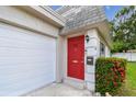 Close up of the front door, which is red, an attached garage, and manicured landscaping at 8447 Orleans N, Pinellas Park, FL 33781