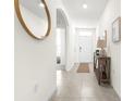 Bright hallway featuring tile flooring, neutral walls, an arched doorway, and stylish decorative mirror at 9098 Forge Breeze Loop, Wesley Chapel, FL 33545