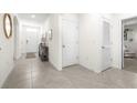 Bright hallway featuring tile flooring, neutral walls, and access to multiple rooms at 9098 Forge Breeze Loop, Wesley Chapel, FL 33545