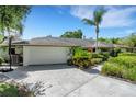 Front exterior featuring a well-manicured lawn, a two-car garage, and mature landscaping at 1000 Chatham Ct, Safety Harbor, FL 34695