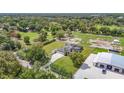 Estate aerial view showcasing a spacious home, with a green lawn, fenced paddock, and large outbuilding at 12637 Tyler Run Ave, Odessa, FL 33556