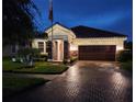 Charming one-story home featuring a tile roof, paver driveway, and well-maintained landscaping at twilight at 13113 Green Violet Dr, Riverview, FL 33579