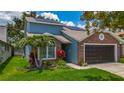 Two-story blue house with a brick facade, solar panels, beautiful landscaping, and a two-car garage at 2254 Springrain Dr, Clearwater, FL 33763