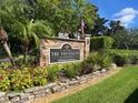 Community sign for The Fountains at Countryside, featuring lush landscaping and an American flag at 2500 Winding Creek Blvd # B105, Clearwater, FL 33761