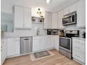 Bright kitchen featuring stainless steel appliances, white cabinets, and light wood-style flooring at 2822 W Bay Ave, Tampa, FL 33611