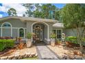 Close up of a home's entrance, beautifully landscaped with mature plants, gravel, stone accents, and a small fountain at 3273 Tanglewood Trl, Palm Harbor, FL 34685