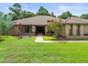Traditional brick home featuring a lush green lawn and flowering trees at 3305 Westmoreland Dr, Tampa, FL 33618