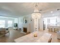 Open-concept living and dining area with a decorative chandelier, fireplace, and view into the bright kitchen at 434 77Th Ave, St Pete Beach, FL 33706