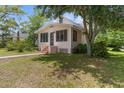 Exterior shot showcasing a cute single-Gathering home with a screened porch, lawn and mature trees at 459 Bell Ave, Brooksville, FL 34601